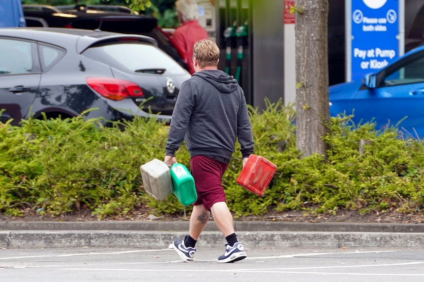 A man carries containers to a petrol station