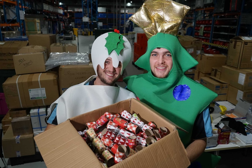Cathal Murray and Joe Veitch are holding a box of Christmas crackers. One is dressed as a pudding and the other a tree.