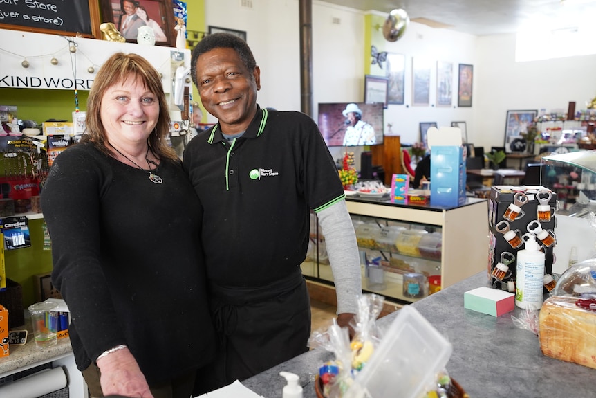 A white woman has has arm around a black man inside a rural general store.