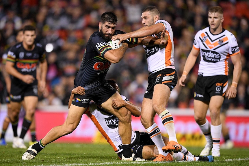 James Tamou stands as he attempts to fend off the tackle of Robbie Farah.