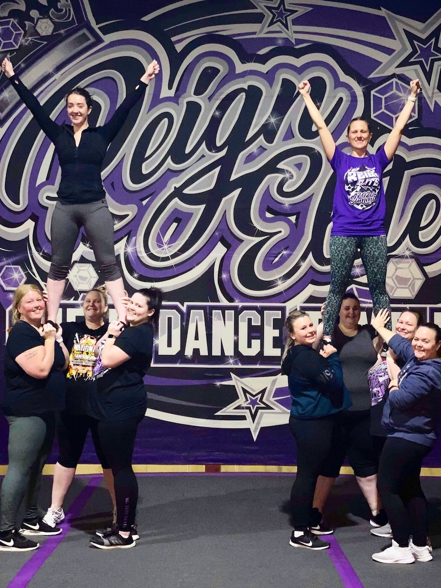 Members of an adult cheer team pose for a photo.