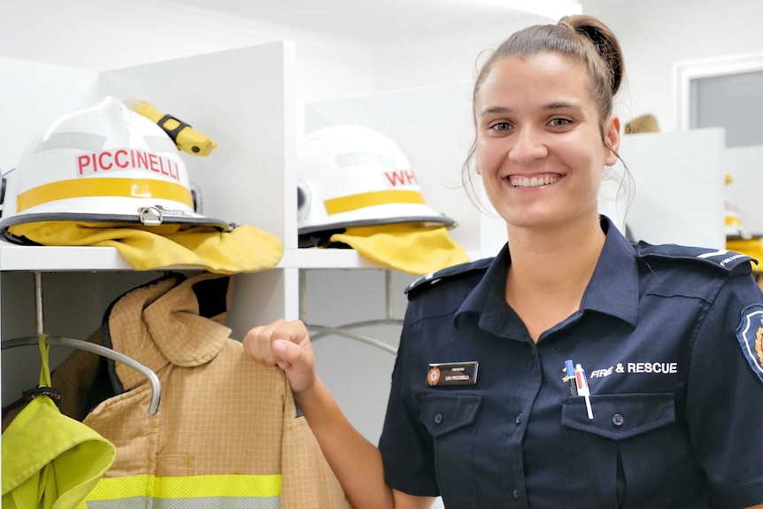 Standing next to firefighting uniforms.