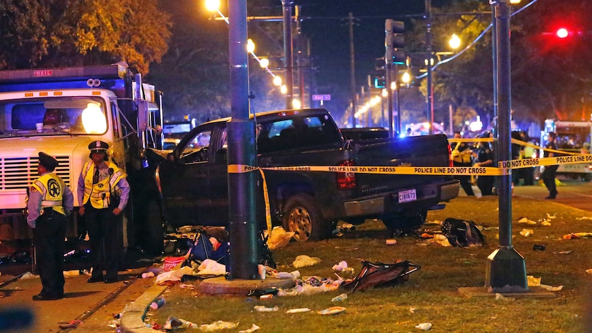 Police stand next to a pickup truck that slammed into a crowd in New Orleans.