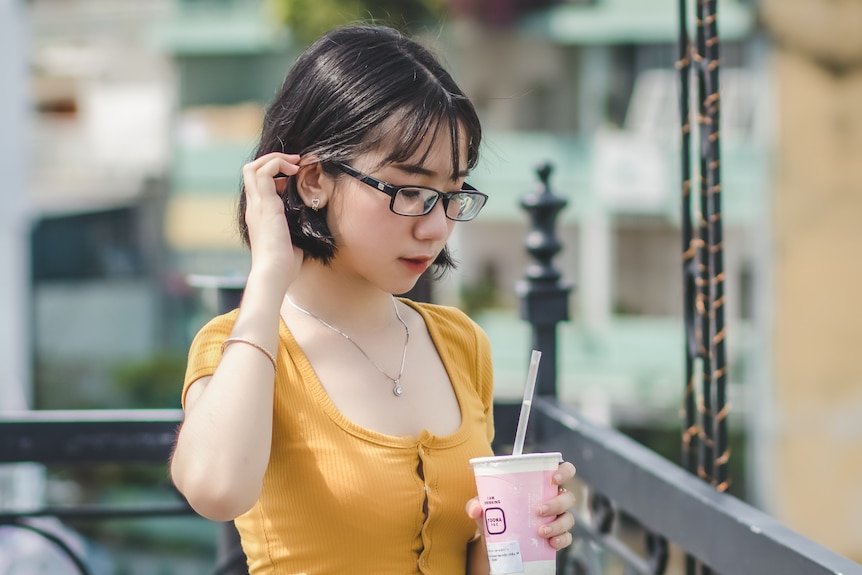 A woman with a cup in her hand in the sun outside