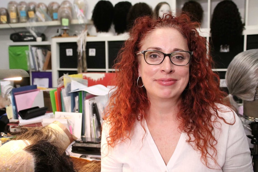 a woman with red hair sitting in an art studio