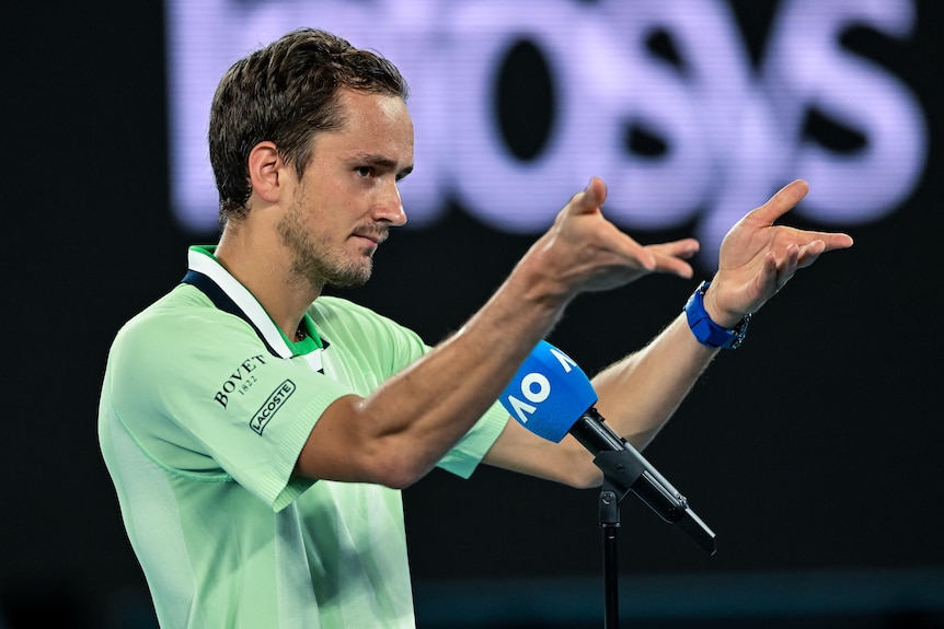 Daniil Medvedev holds up his hands while talking on a microphone