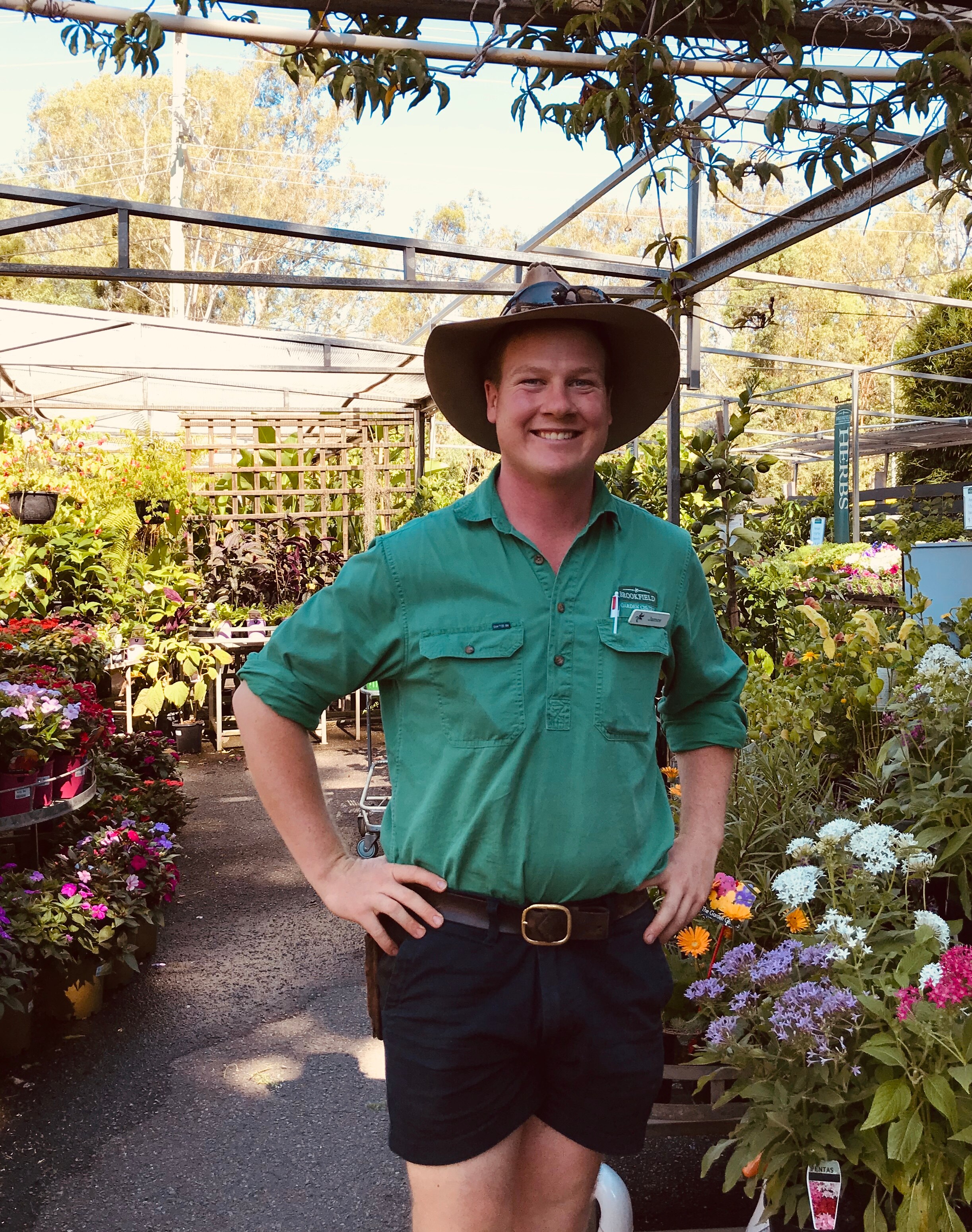 Young man in a killer hat, shorts and button down shirt smiling to the camera