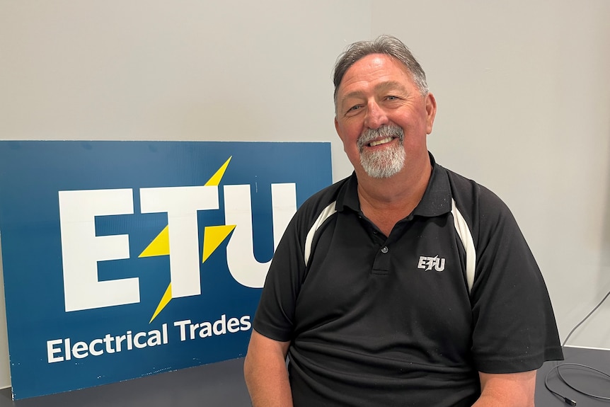 A middle-aged man in front of an ETU sign