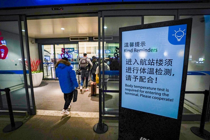 The exterior of an airport with a body temperature test sign