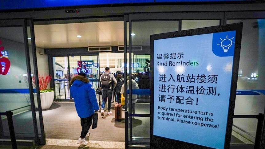 The exterior of an airport with a body temperature test sign