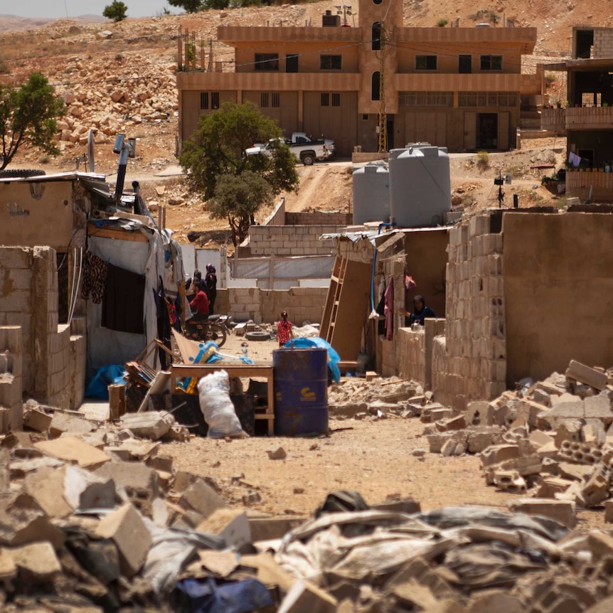 Several concrete homes party demolished, with bricks and rubbish lying on the ground.