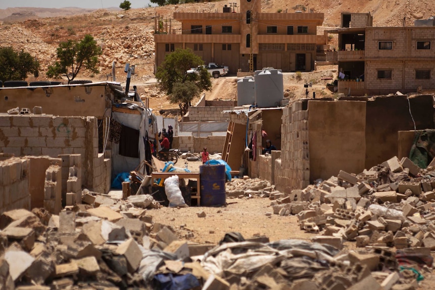 Several concrete homes party demolished, with bricks and rubbish lying on the ground.