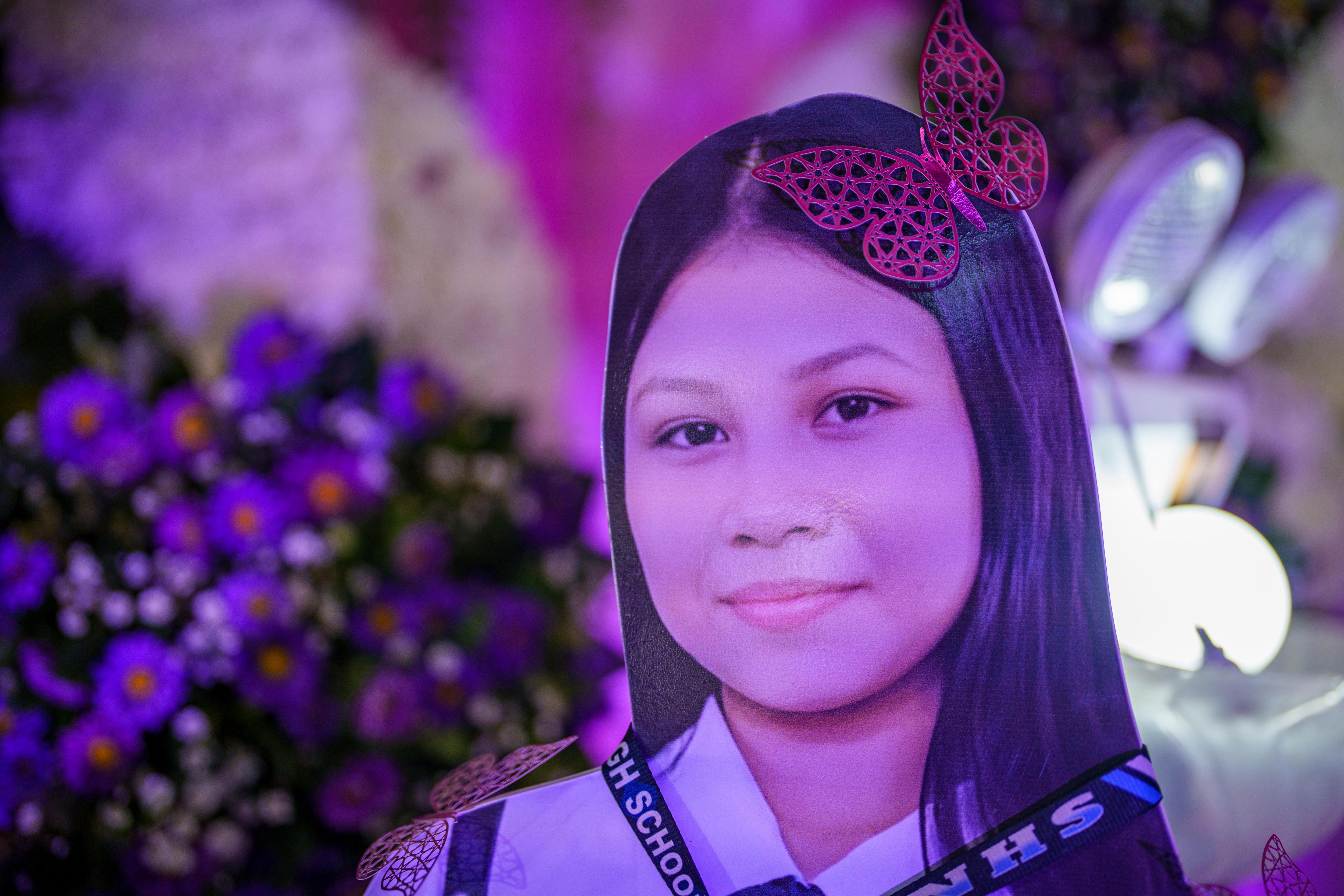 A cardboard cutout of a 14 year old Filipino schoolgirl bathed in purple light at a memorial service.