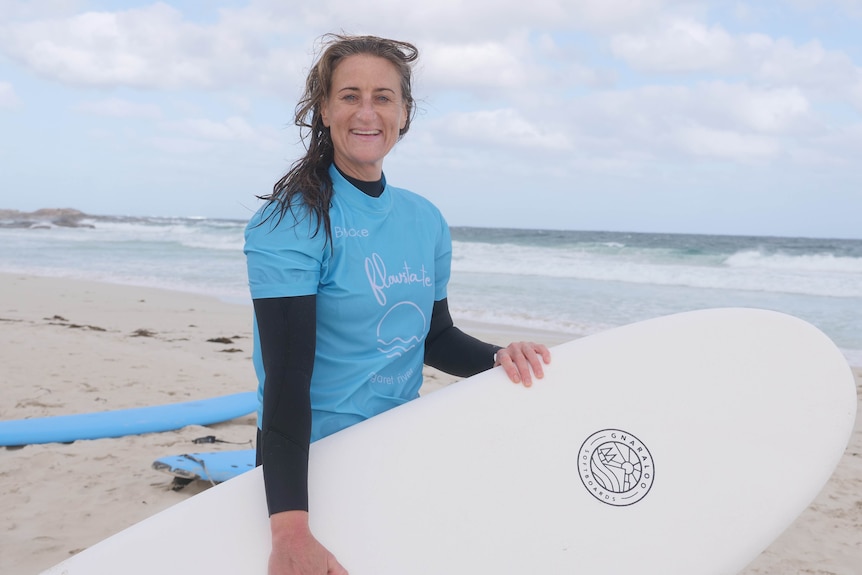 A woman holding a surfboard at a beach