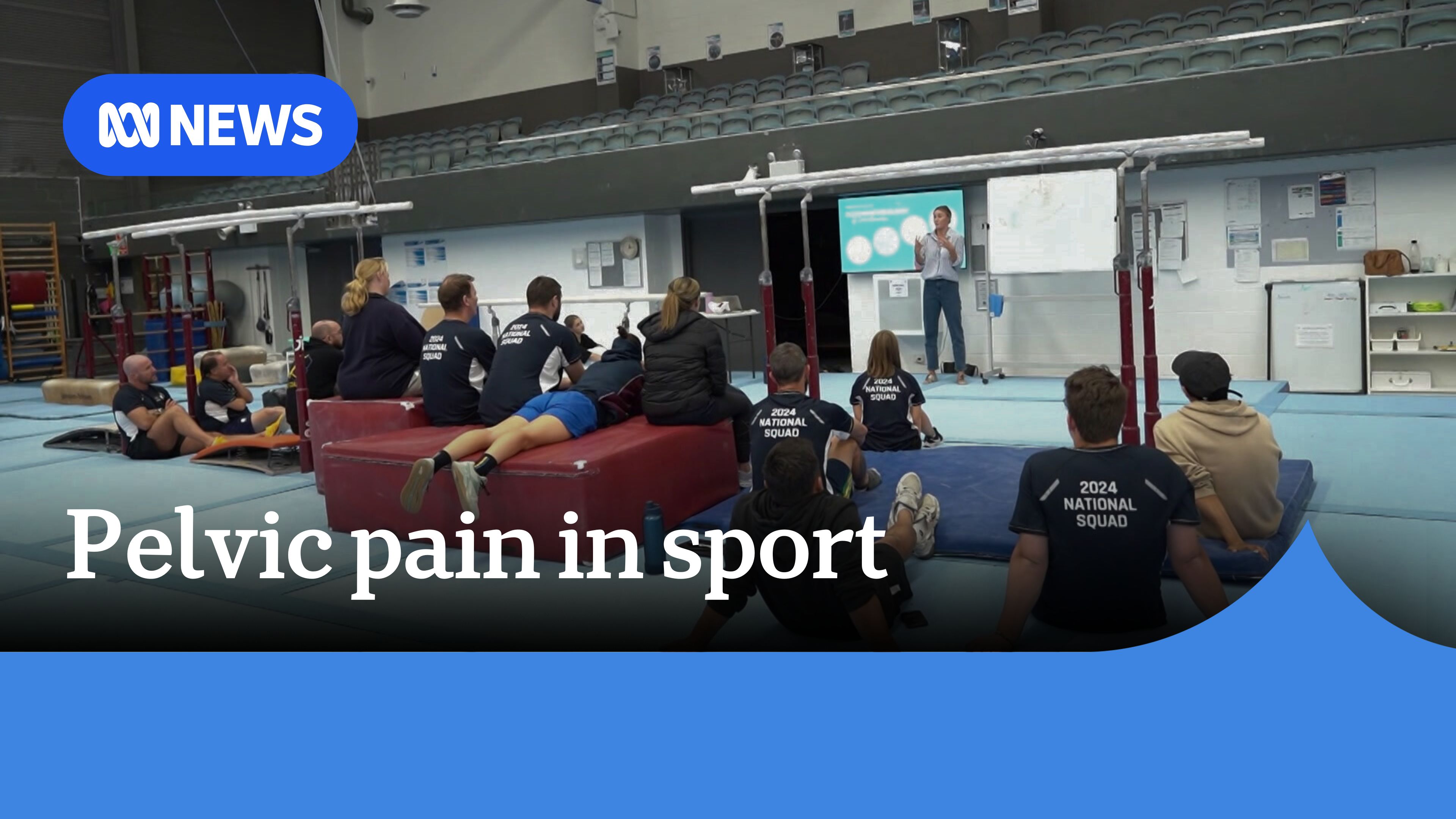 Pelvic Pain In Sport: Elite athletes sit on gymnasium floor looking at whiteboard for workshop.