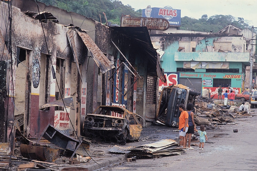 Burned cars and buildings stretch along a street in Panama.