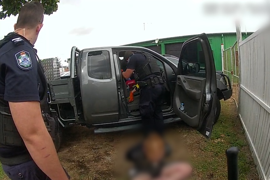 Body worn camera vision captures three police officers surrounding a ute which had the driver door open. 