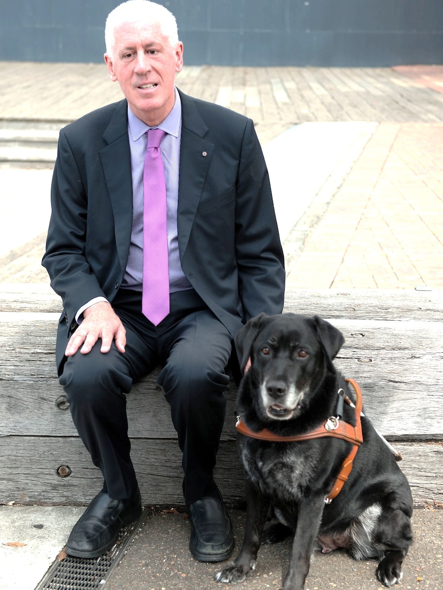 Graeme Innes sits with his guide dog.