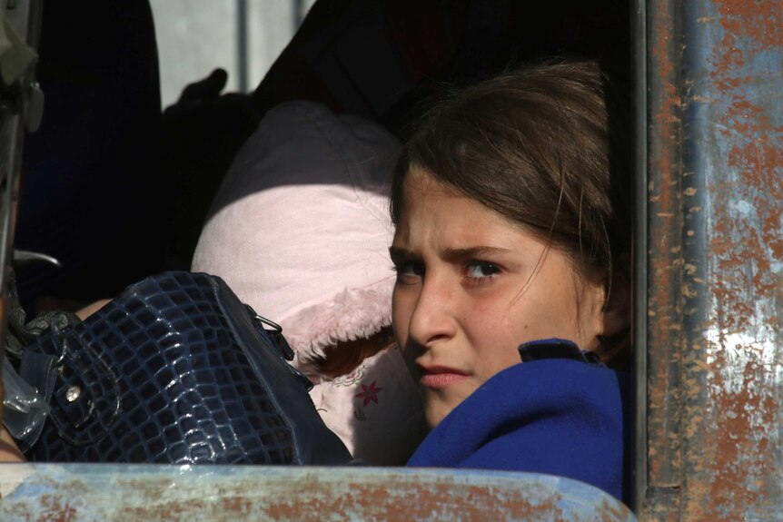 A girl who fled areas of conflict in the back of a vehicle.