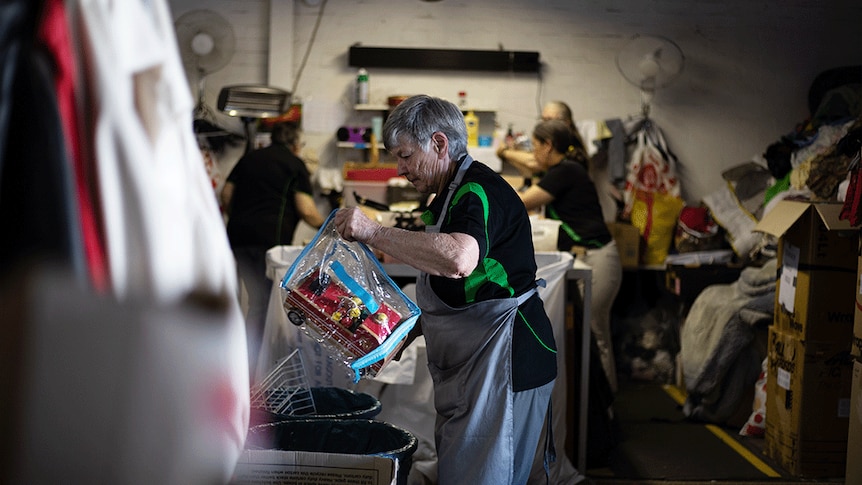 a group of women sort through second-hand goods