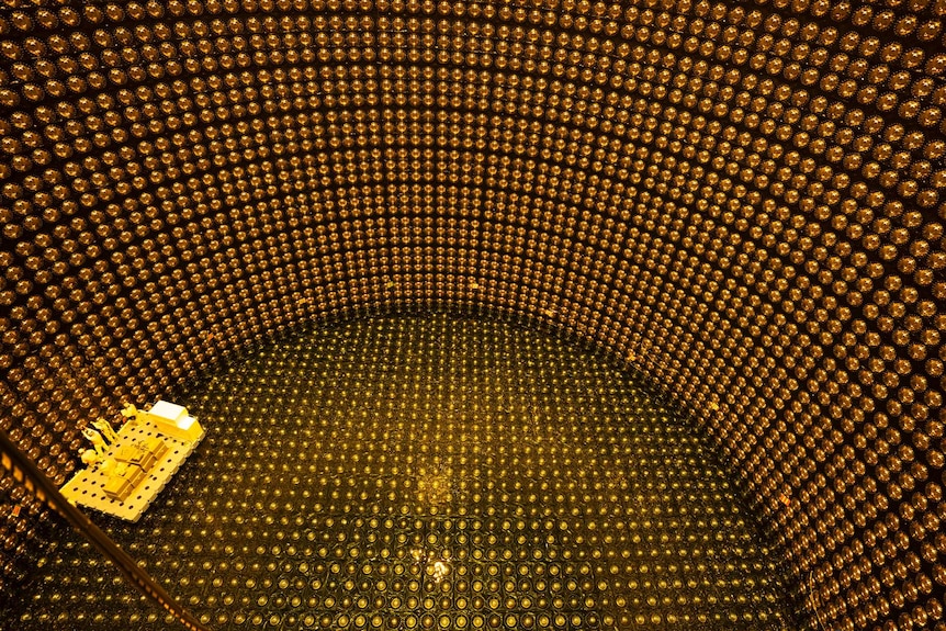 View from above looking down inside observatory and crew in yellow suits on small platform repairing golden bulbs.