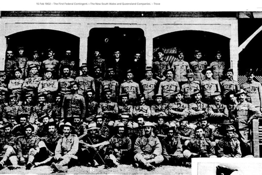 Group photo of army men in uniform sitting and standing in lines.