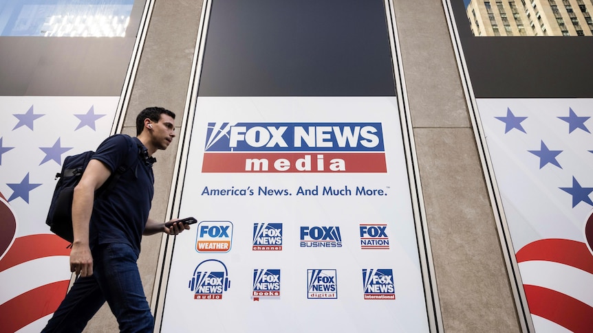 - A person walks past a building which says Fox News.