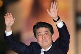 Head and shoulders shot of Shinzo Abe waving with both hands.