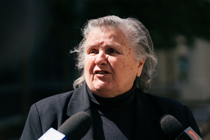 A head and shoulders shot of an older woman outside court.