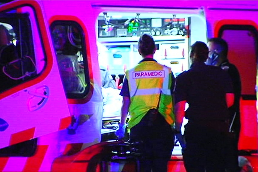 Paramedics stretcher a man into an ambulance.