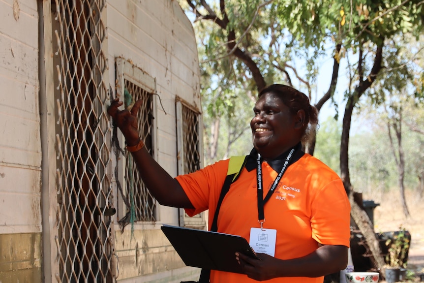 A woman knocks on the door of a caravan in a remote NT community. 