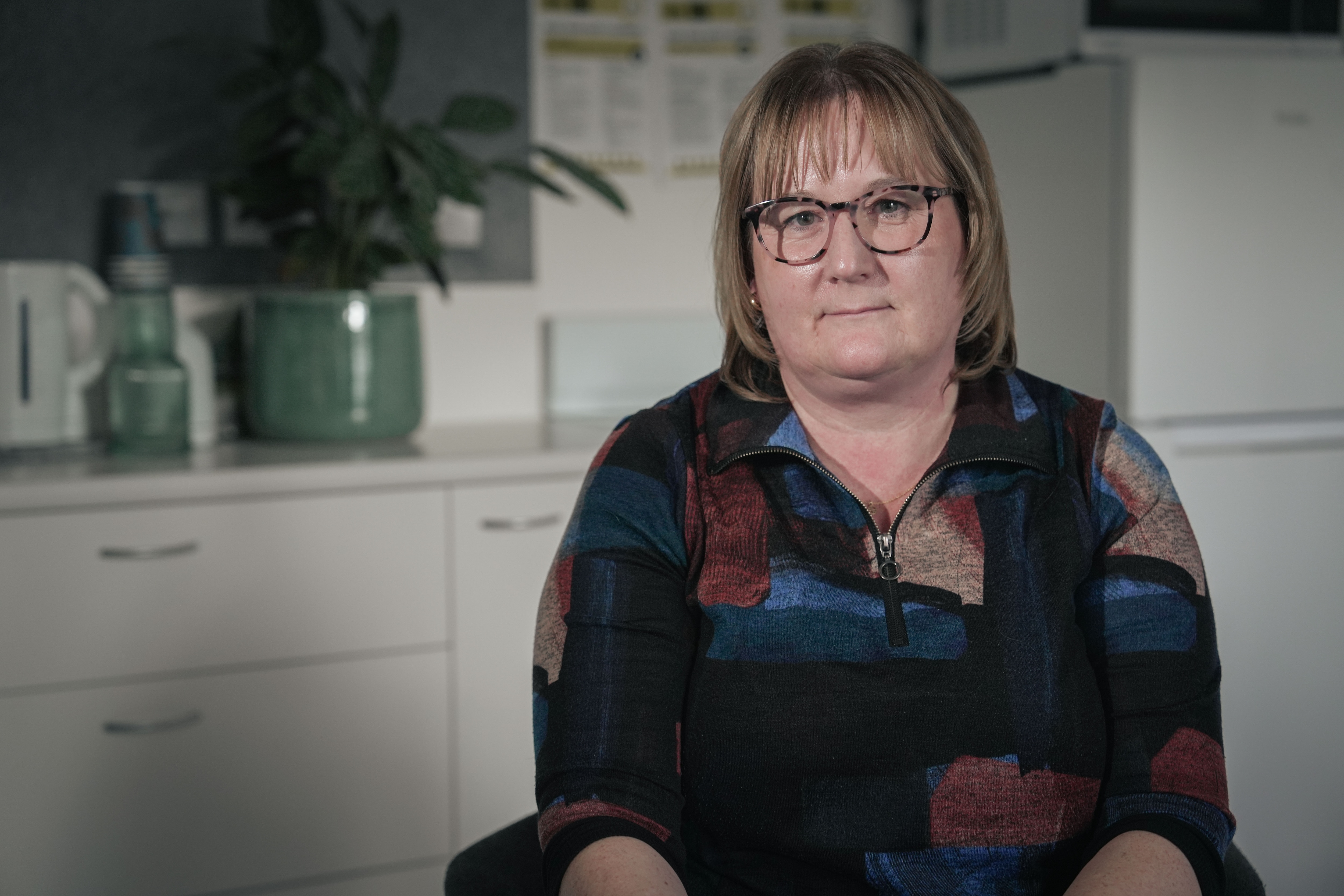 Janet Saunders sitting in front of a kitchen.
