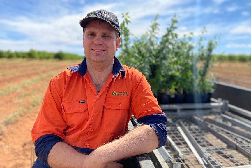 A man sitting on a trailer next to the trees.