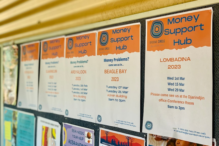 A line of posters pinned on a wall outside saying 'Money Support Hub'