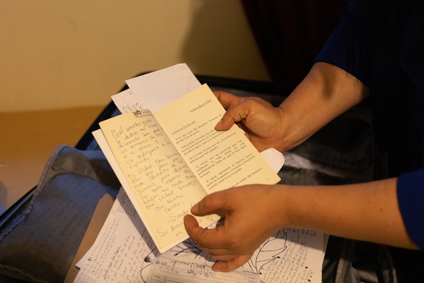 A woman holds cards and drawing from her children.