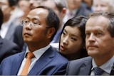 An unidentified woman whispers in Mr Huang's ear as he and Bill Shorten look into the distance
