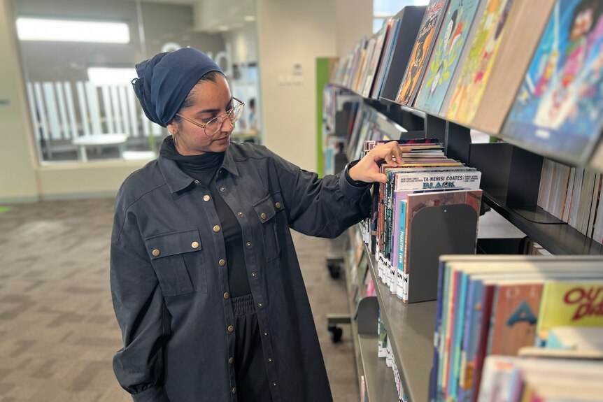 A woman wearing a hijab looking at a bookshelf