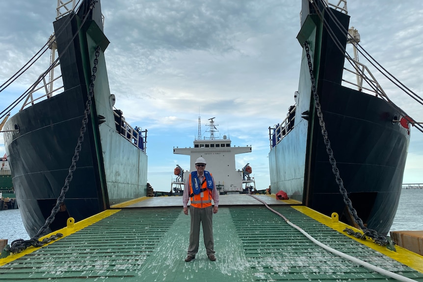 A man stands in front of a ship at a port