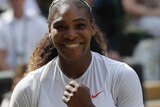 Serena Williams looks smiling to the camera with her left fist clenched.