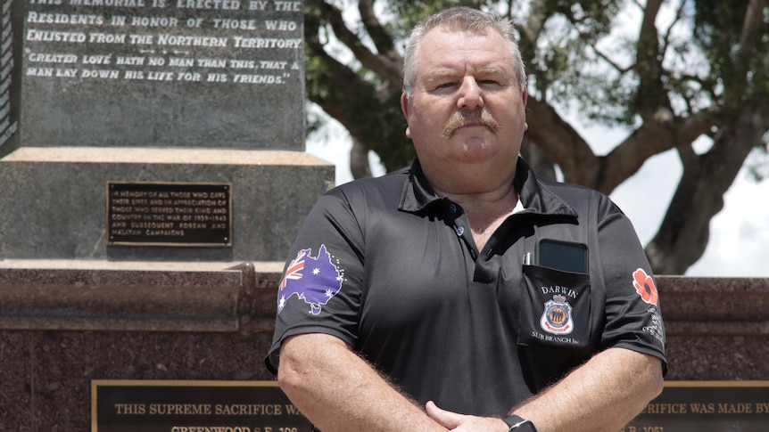 A man standing in front of the Darwin Cenotaph.