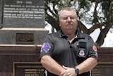 A man standing in front of the Darwin Cenotaph.