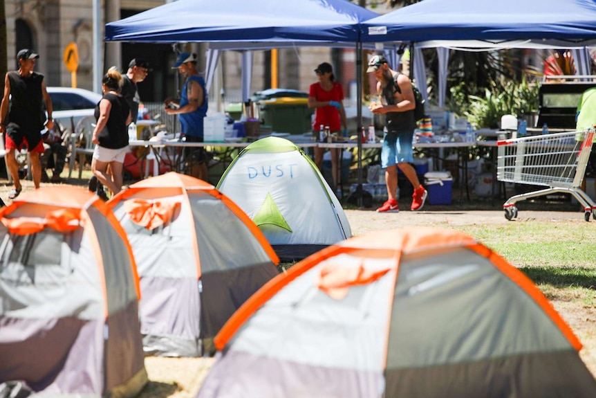 A series of one-man tents are pitched in front of two temporary gazebos serving food.