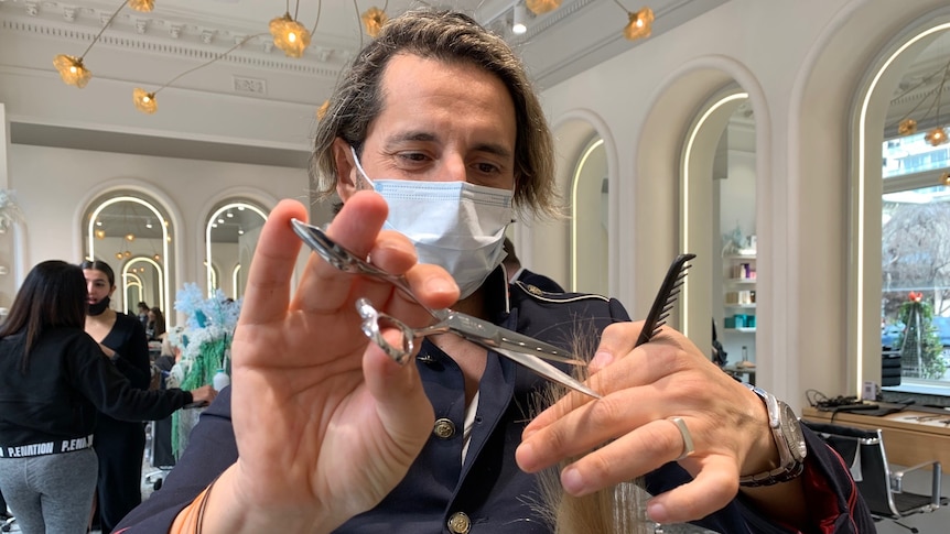 Melbourne hairdresser Joey Scandizzo cuts a woman's hair.