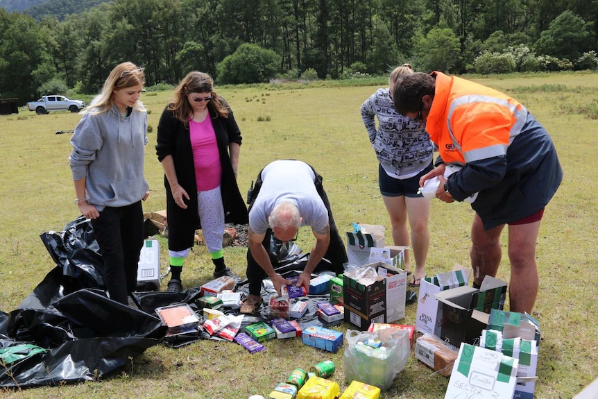 Five campers sort through food supplies on the ground.