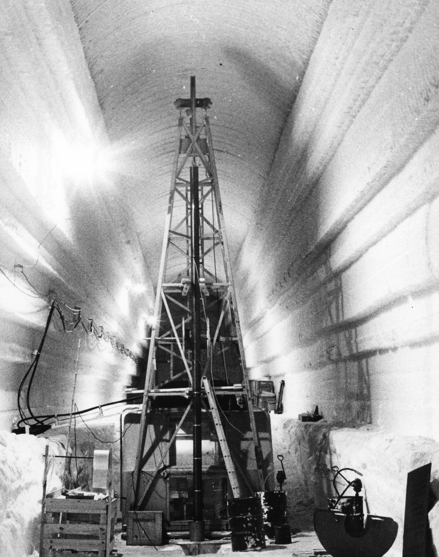 A black and white photo of a drill rig under the ice.