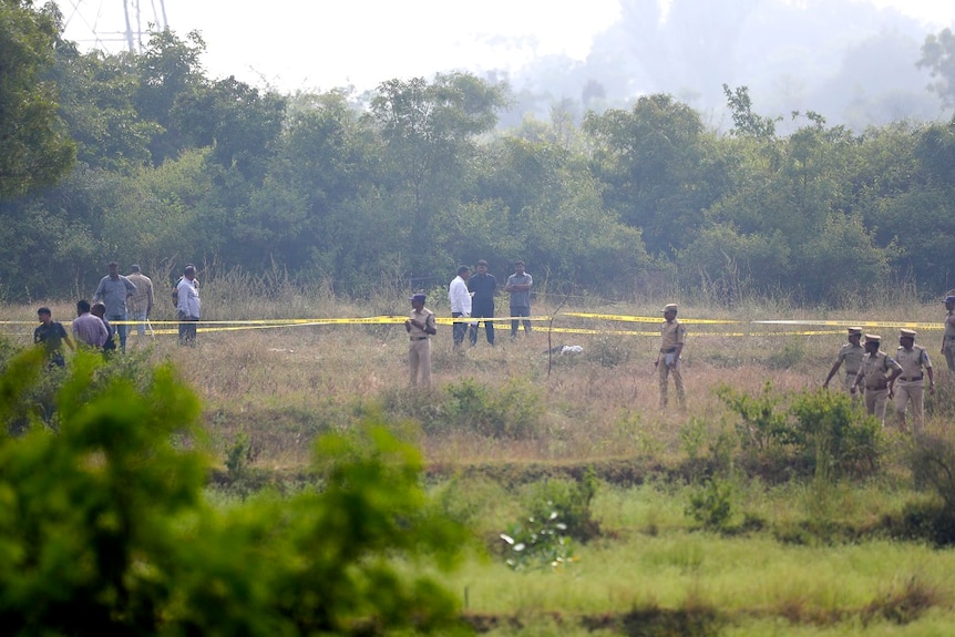 Indian policemen stand guard the area where rape accused were shot in Shadnagar some 50 kilometers or 31 miles from Hyderabad.