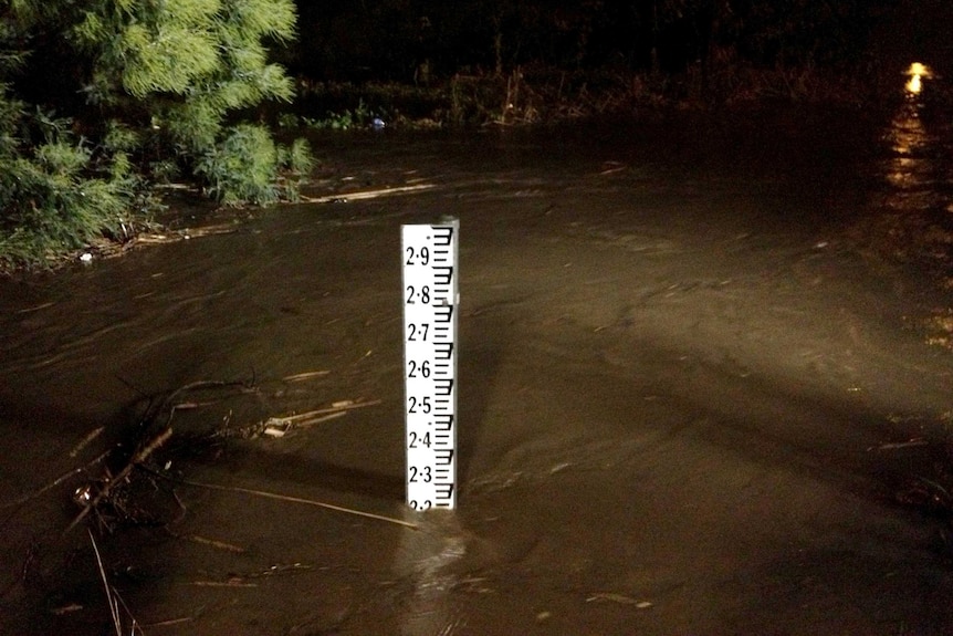 Floodwaters flow around a flood marker at Traralgon.