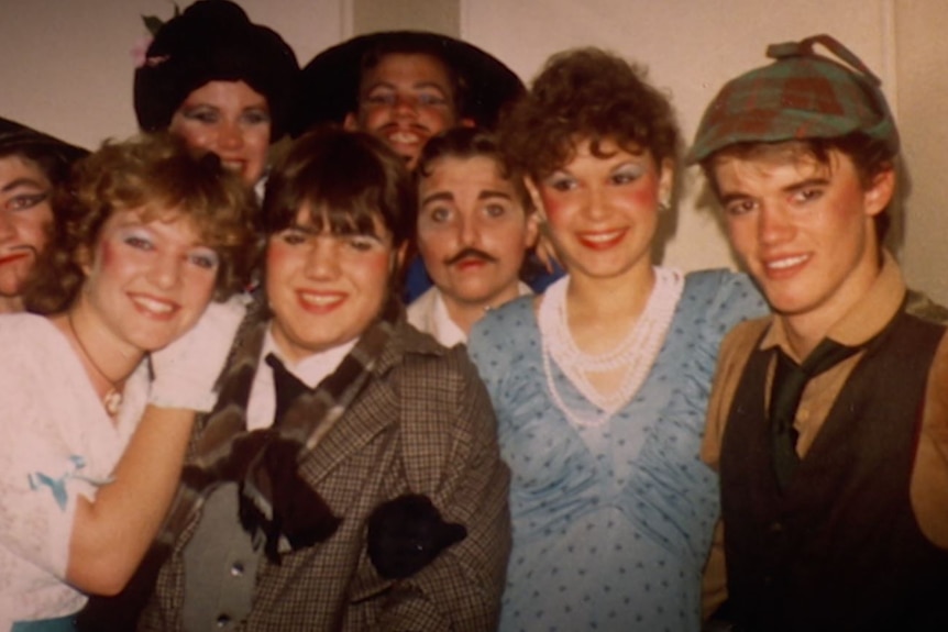 A group photo of smiling teenagers in performance costumes