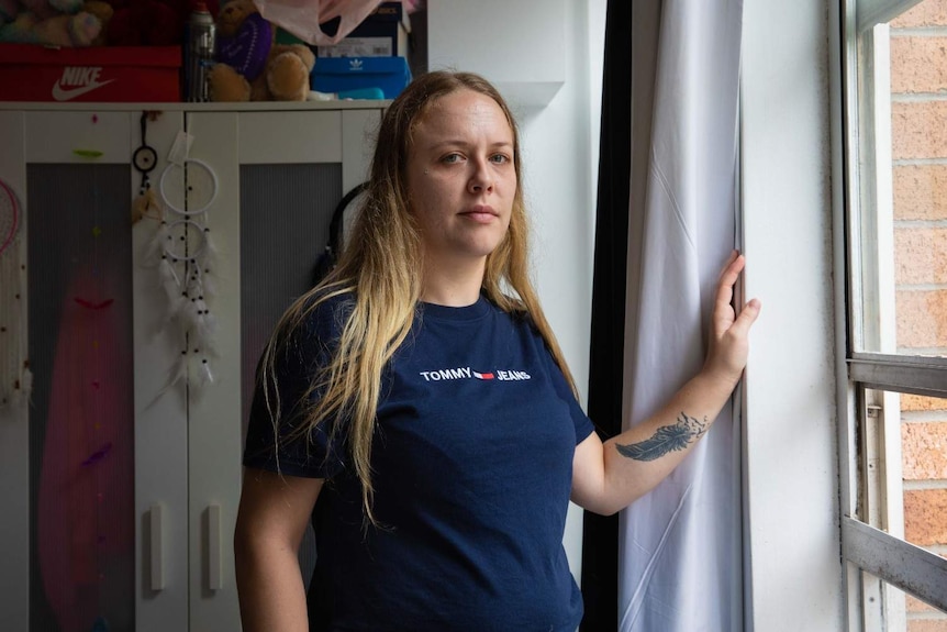 A girl stands at a bedroom window