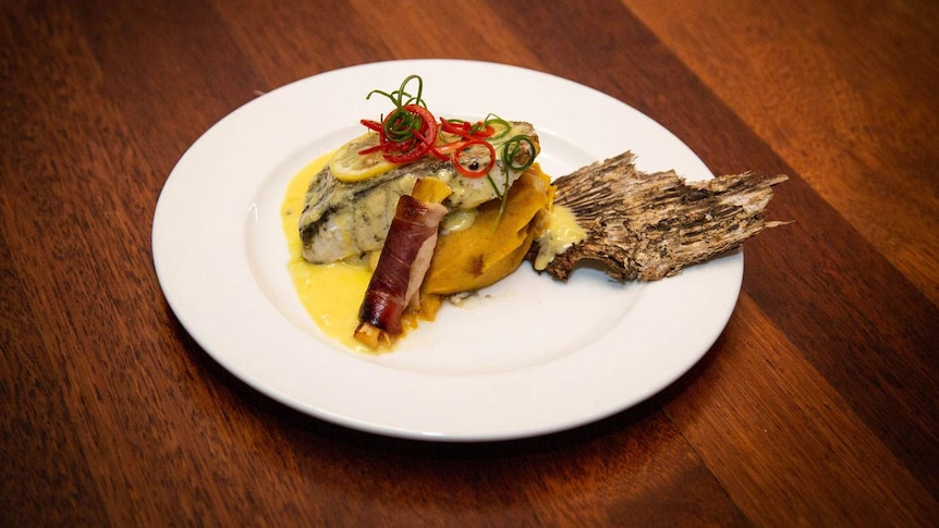 Paperbark smoked local barramundi on a white plate.